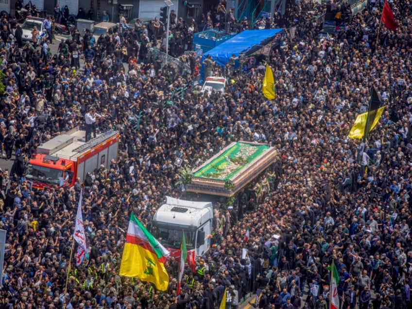 TEHRAN, IRAN - MAY 22: Iranians follow a truck carrying coffins of the late President Ebrahim Raisi and his companions, who were killed in a helicopter crash, during a funeral ceremony for them on May 22, 2024 in Tehran, Iran. Raisi died after his helicopter went down in a foggy mountain region near the Azerbaijan border on Sunday. The crash also claimed the lives of Foreign Minister Hossein Amir-Abdollahian and several other officials. (Photo by Majid Saeedi/Getty Images)