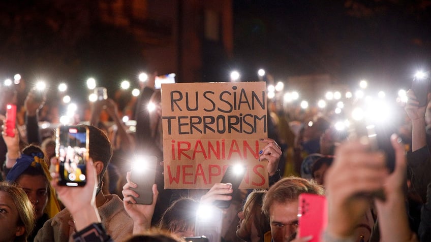 protesters holding up cell phones; one holds sign protesting 'russian terrorism...'