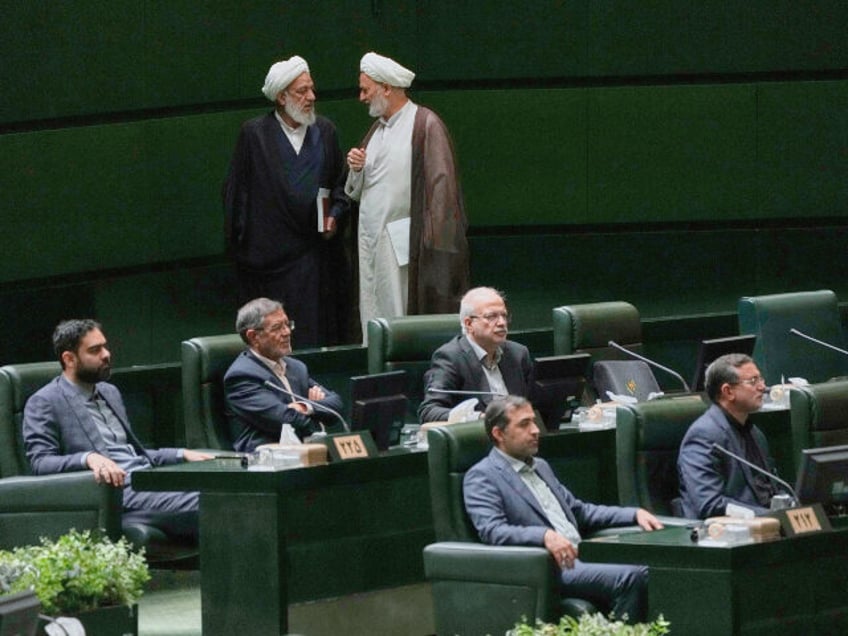 Two Iranian lawmakers talk at the parliament during a memorial, in Tehran, Iran, Wednesday