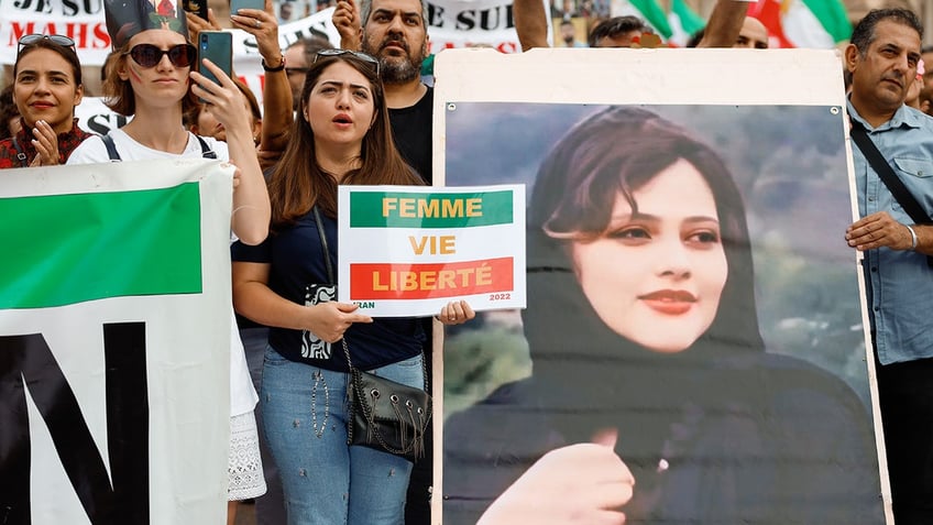 French protester holds poster of Amini