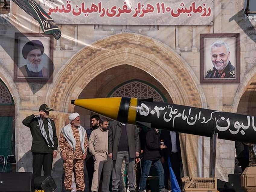 A commander of the Islamic Revolutionary Guard Corps (IRGC) salutes as an Iranian-made mis