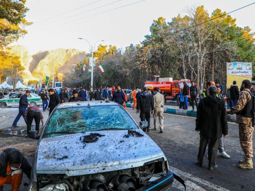 This picture shows people and Iranian emergency personnel at the site where two explosions in quick succession struck a crowd marking the anniversary of the 2020 killing of Guards general Qasem Soleimani, near the Saheb al-Zaman Mosque in the southern Iranian city of Kerman on January 3, 2024. Iran's president Ebrahim Raisi condemned on January 3 twin blasts that killed at least 103 people in the country's south where crowds gathered to mark the killing of general Qasem Soleimani. (Photo by Sare Tajalli / ISNA / AFP) (Photo by SARE TAJALLI/ISNA/AFP via Getty Images)