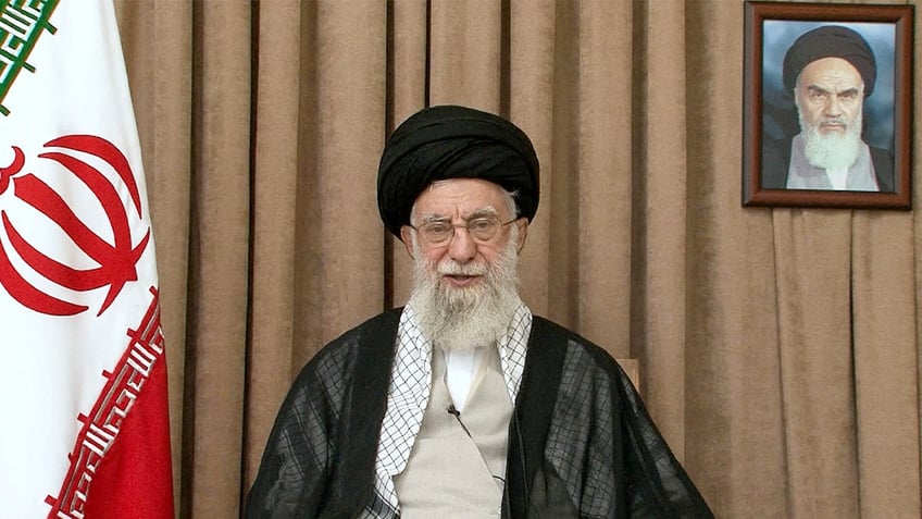 Ayatollah Ali Khamenei sits next to Iranian flag