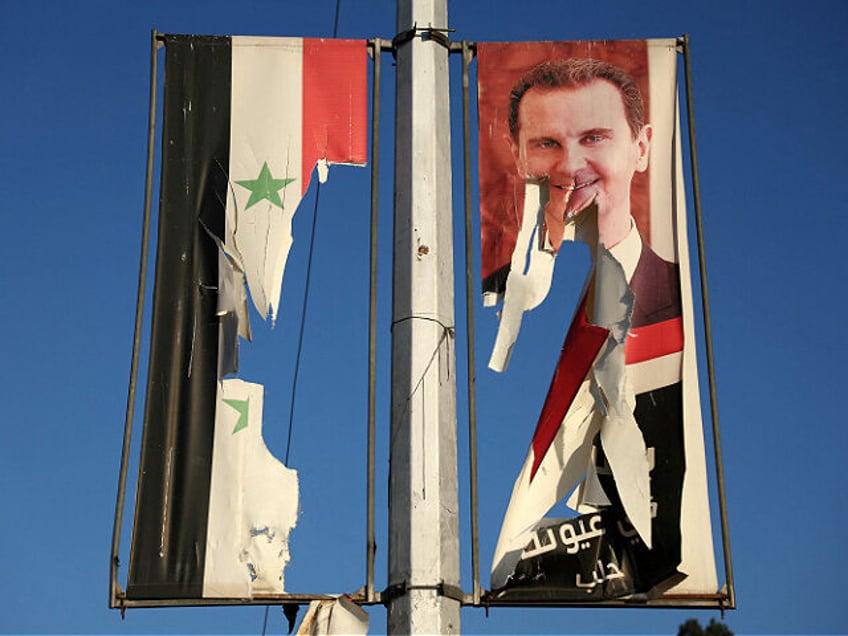 A billboard bearing a picture of Syria's President Bashar al-Assad and a national flag are