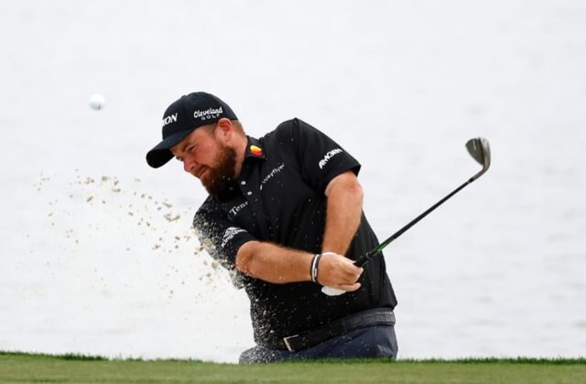 Ireland's Shane Lowry plays out of a bunker on the way to a birdie at 18 and a share of th