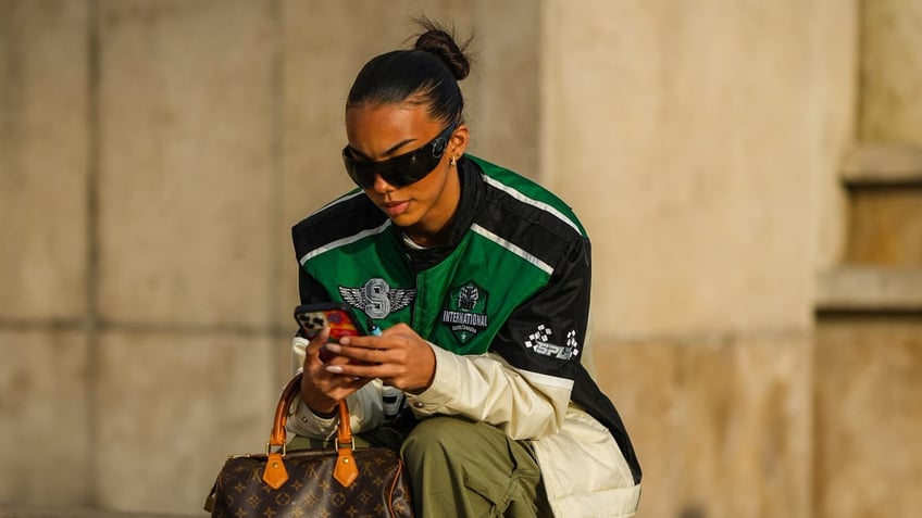 woman sitting typing on her iPhone