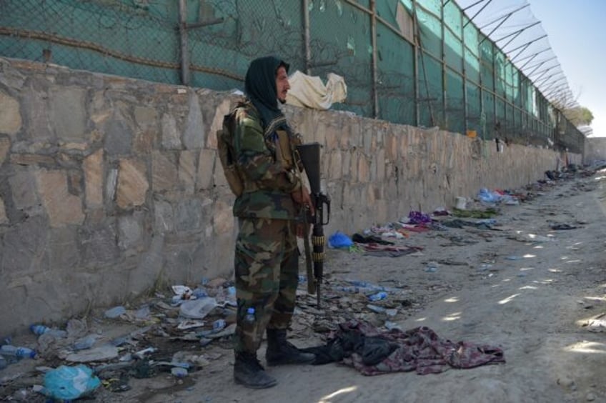 A Taliban fighter stands guard at the site of the August 26 bomb which killed scores of pe