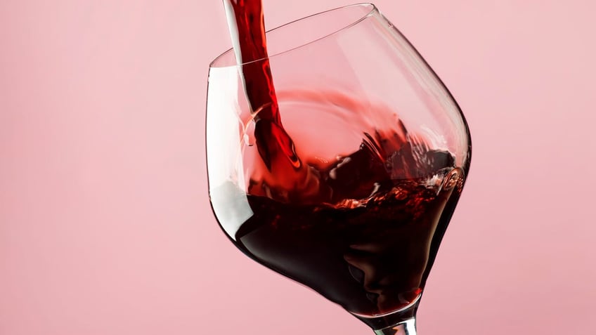 French dry red wine, pours into glass, trendy pink background