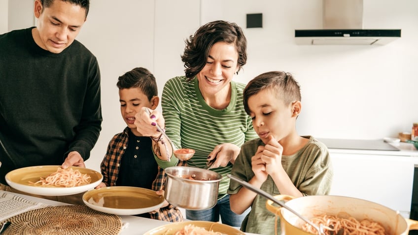 parents and kids serving pasta