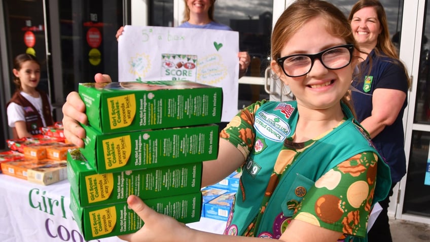 Girl Scout Isabella Tomerlin holds four boxes of Thin Mints in her hand after a sale.