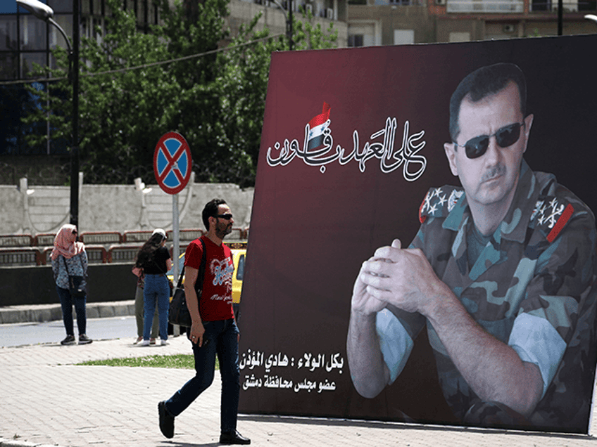 A Syrian man walks past a giant portrait of President Bashar al-Assad at the Umawiyin square in Syria's capital Damascus on May 3, 2021, ahead of this month's presidential elections. - A Syrian former minister and a member of the Damascus-tolerated opposition will face Bashar al-Assad in this month's presidential election, the constitutional court said Monday. The Assad-appointed body approved only three out of 51 applications to stand in the May 26 ballot, among them the 55-year-old president himself, (Photo by LOUAI BESHARA / AFP) (Photo by LOUAI BESHARA/AFP via Getty Images)