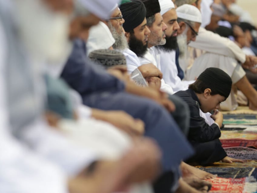 A child leans forward as people gather for a large communal prayer at the velodrome of Sai