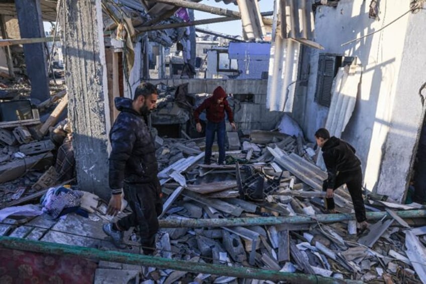 Palestinians search through the rubble of a building following an Israeli strike in the southern Gaza Strip on Tuesday