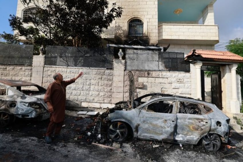 A man points to damage in his house after an attack by Jewish settlers on the Palestinian