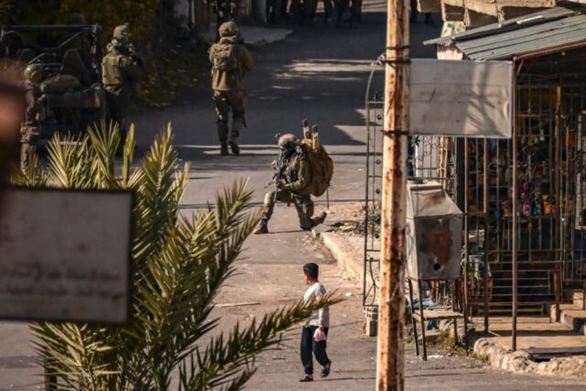 A child looks on as Israeli soldiers patrol in Jubata al-Khashab, in the UN-patrolled Gola