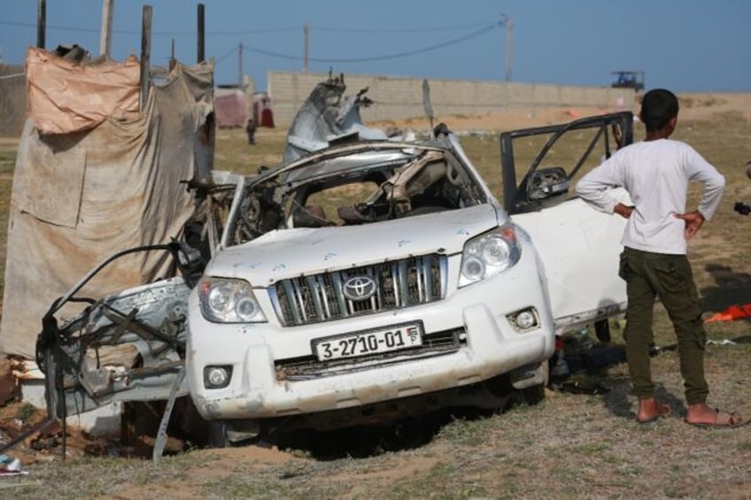 People gather around a car used by US-based aid group World Central Kitchen that was hit b