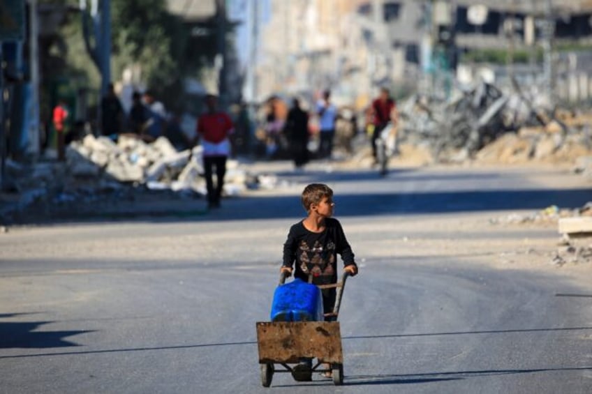 A boy carries water al-Bureij refugee camp in Gaza, where UN agencies have warned of dire