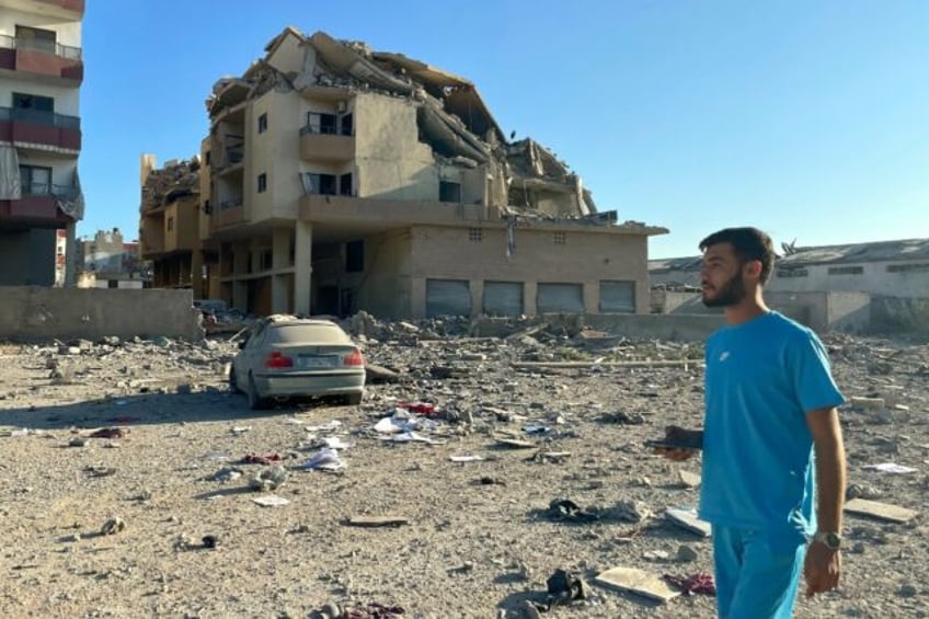 A man walks past destruction caused by Israeli air strikes on the outskirts of the city of