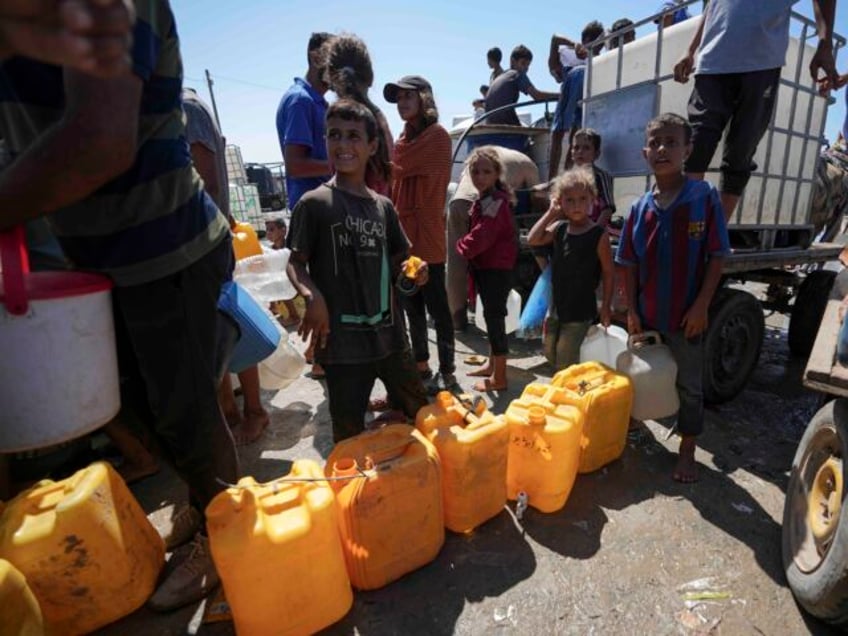 FILE - Displaced Palestinians line up to collect water, in Deir al Balah, central Gaza Str