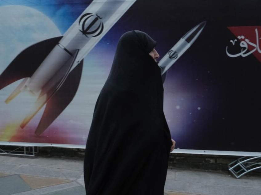 TEHRAN, IRAN - APRIL 17, 2024: People pass by banners posted outside a government affiliat