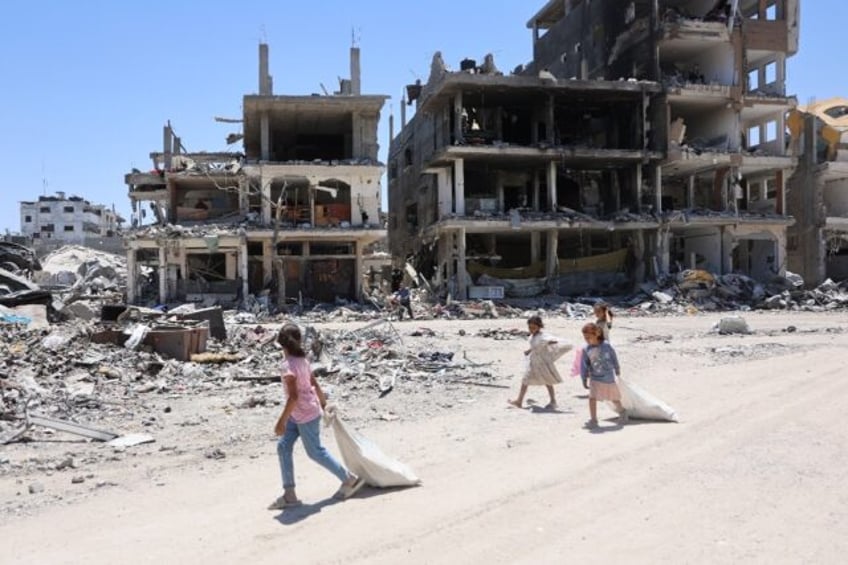 Palestinian children walk past destroyed buildings in the Jabalia refugee camp in northern