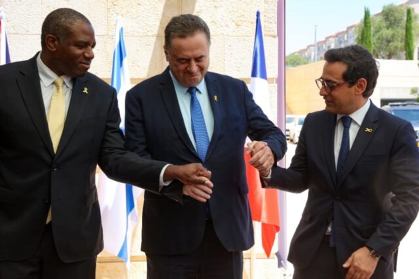 Israel's top diplomat Israel Katz (C) holds hands with his French and British counterparts