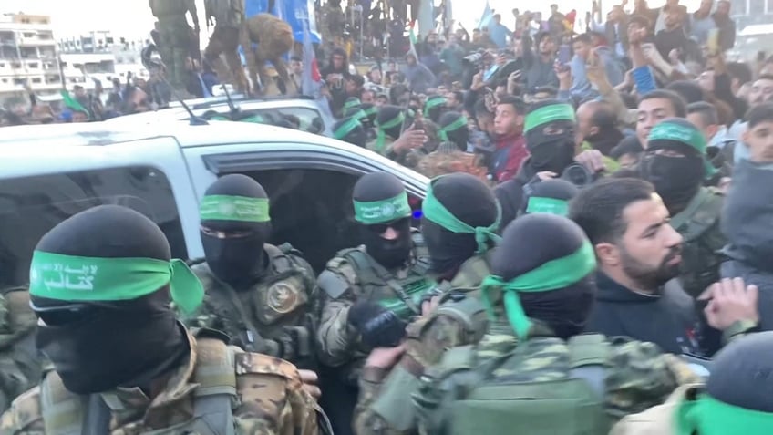 Hamas terrorists emerge in a show of strength escorting Red Cross vehicles carrying three Israeli hostages to be released as part of the cease-fire deal. 