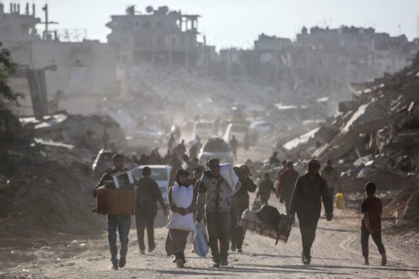 Palestinians carry their belongings as they return to Rafah in southern Gaza, surrounded b