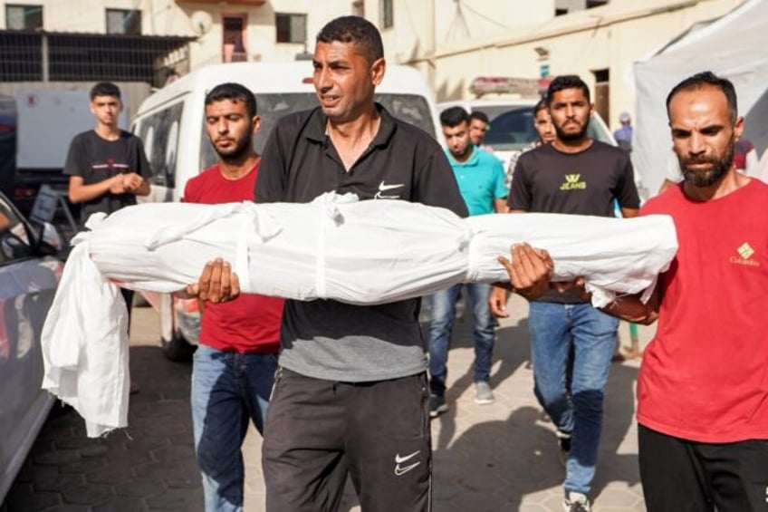 A man carries the body of Abdelrahman Yussef Abu Galambo, 11, who died during Israeli bomb