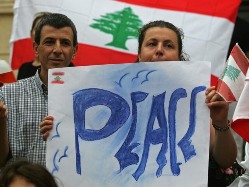 Two people of the Lebanese community of the French riviera hold a banner during a demonstr