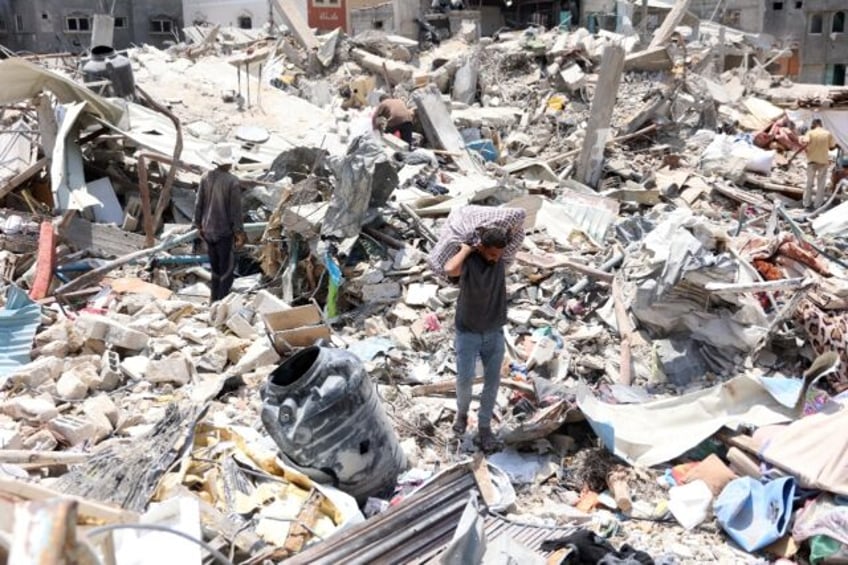 A Palestinian man carries goods he retrieved from under the rubble of a destroyed building