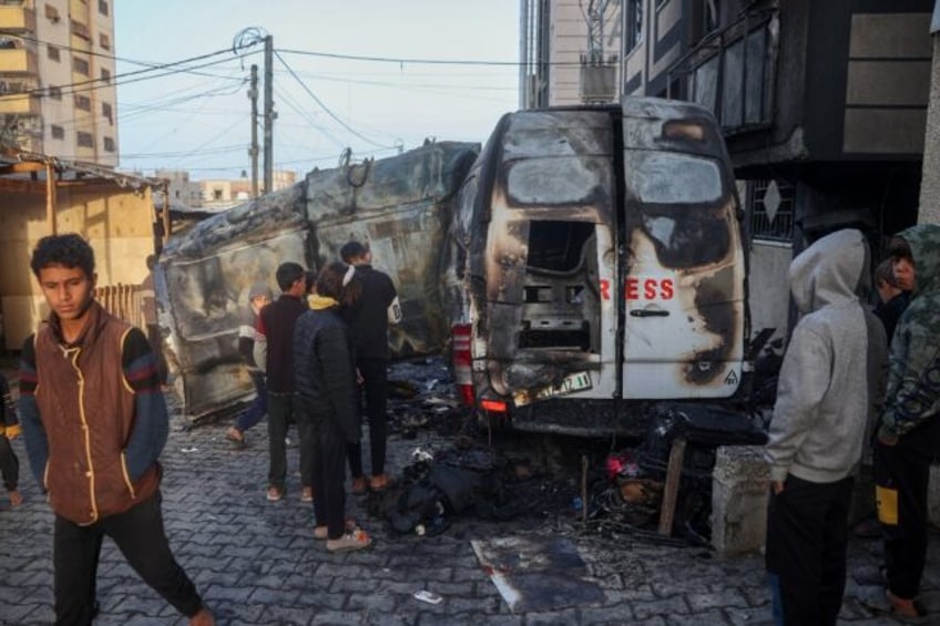 Children check the site of an Israeli strike on a broadcast truck in the Nuseirat refugee