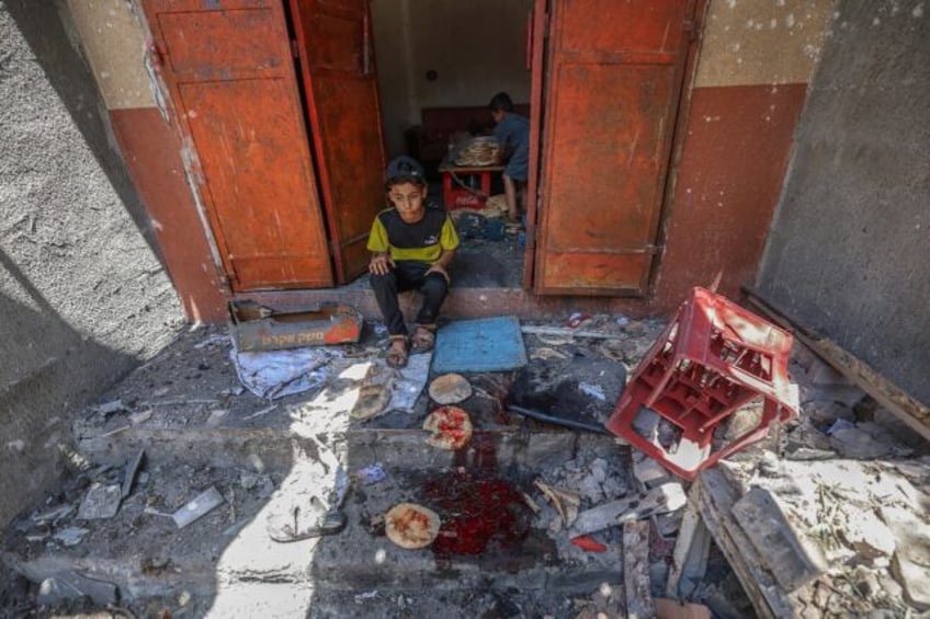 Palestinian boys salvage bread from a makeshift bakery hit in Israeli strikes at the Nusei
