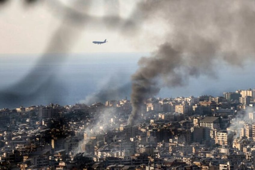 A Middle East Airlines plane approaches Beirut airport, as smoke rises from the site of an