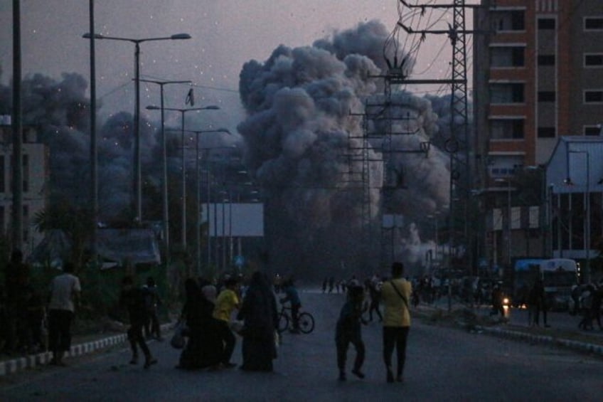 Palestinians watch smoke billowing following an Israeli air strike in Deir al-Balah