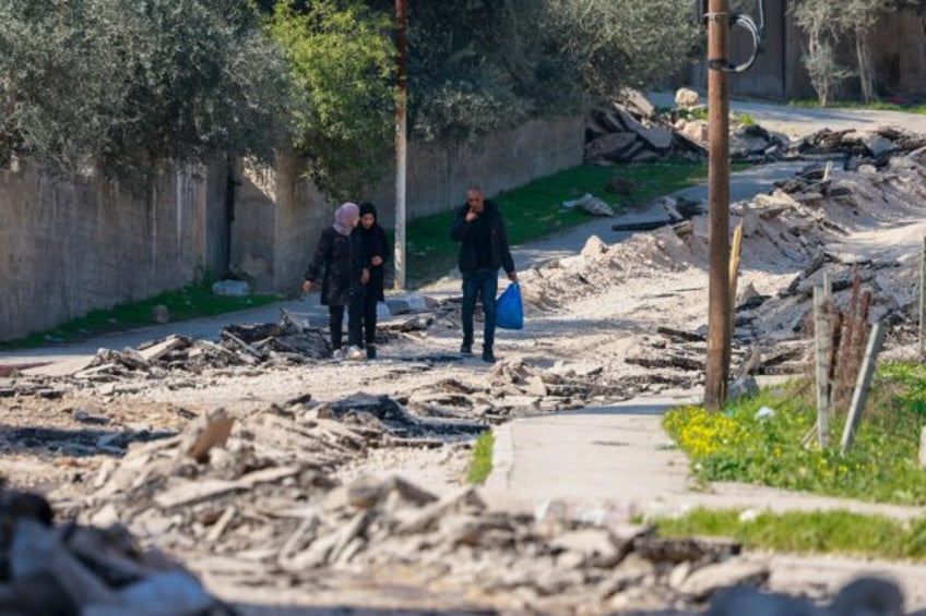 People walk along a road torn up by a bulldozer during an Israeli raid on the Jenin camp f