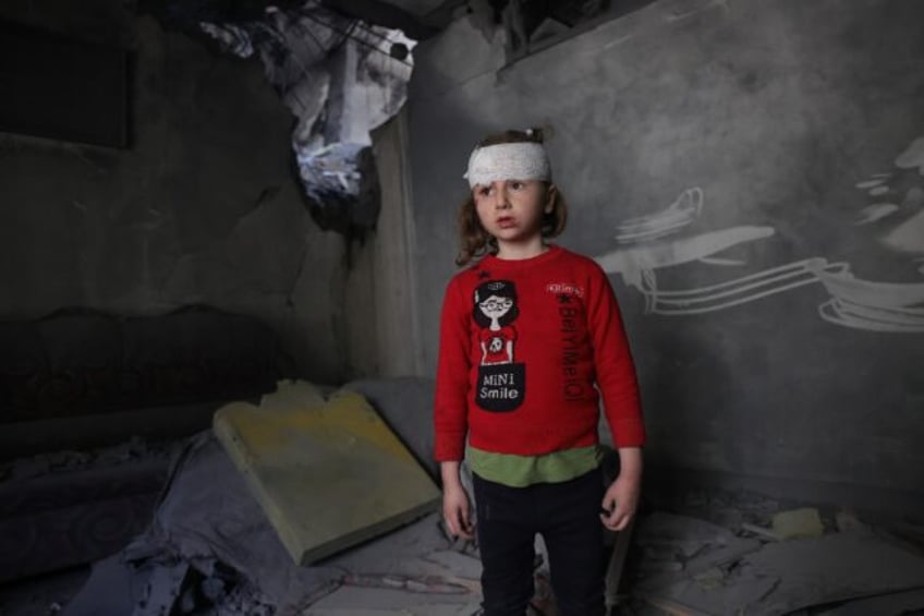 A wounded Palestinian girl stands amid the debris of her family home after overnight Israe