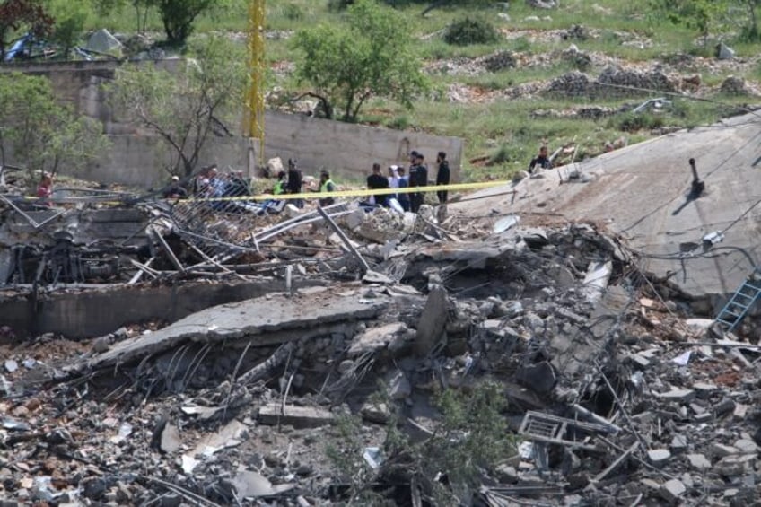 People gather around a destroyed building targeted by Israel in Lebanon's Baablbek distric