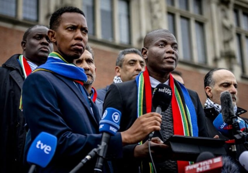 South Africa's Minister of Justice Ronald Lamola (R) talks to reporters after the first day of hearings in a case Israel and its US ally have derided