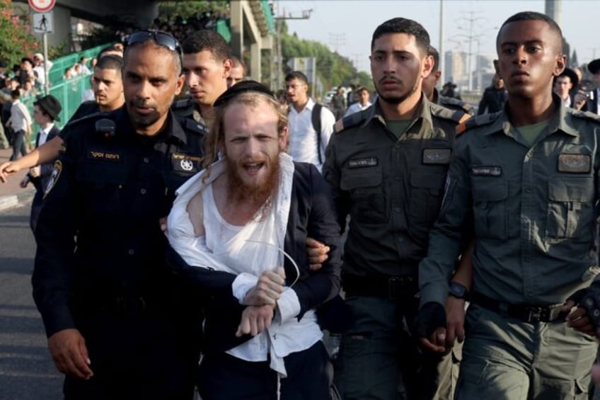 Israeli police detain a man as they they try to disperse ultra-Orthodox Jews blocking a hi