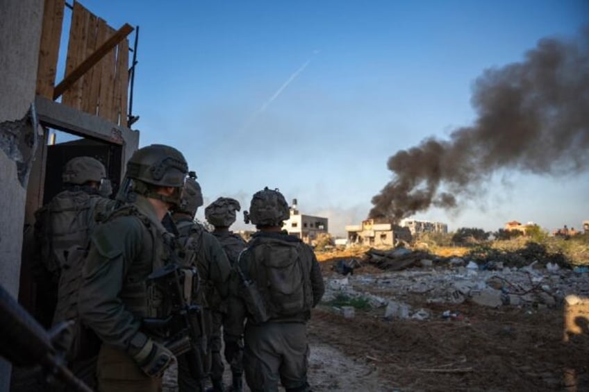 Israeli soldiers watch as smoke billows from a building in Gaza