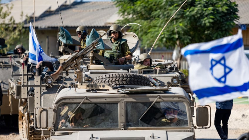 IDF Soldiers ride in armored personnel carriers on October 17, 2023 in Be'eri, Israel.