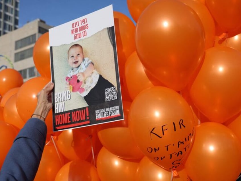 A picture of Kfir Bibas, the youngest hostage to be kidnapped by Hamas militants on the October 7 attack together with his mother and brother, is held in front of balloons as Israelis attend his first birthday celebration in Tel Aviv on January 18, 2024. Kfir Bibas was born on …