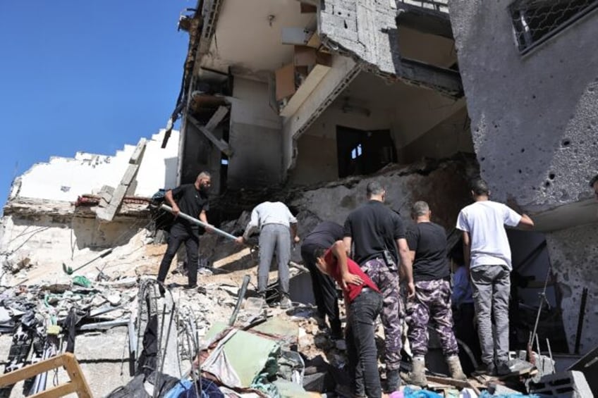 People search the rubble of a building hit by bombardment at the Nur Shams refguee camp in