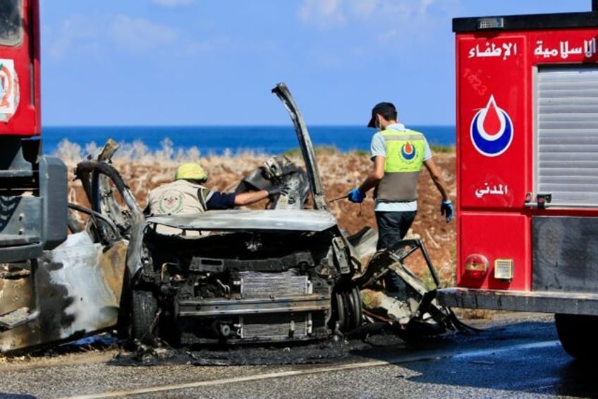 Civil Defence teams inspect a charred car that was reportedly hit by an Israeli drone stri