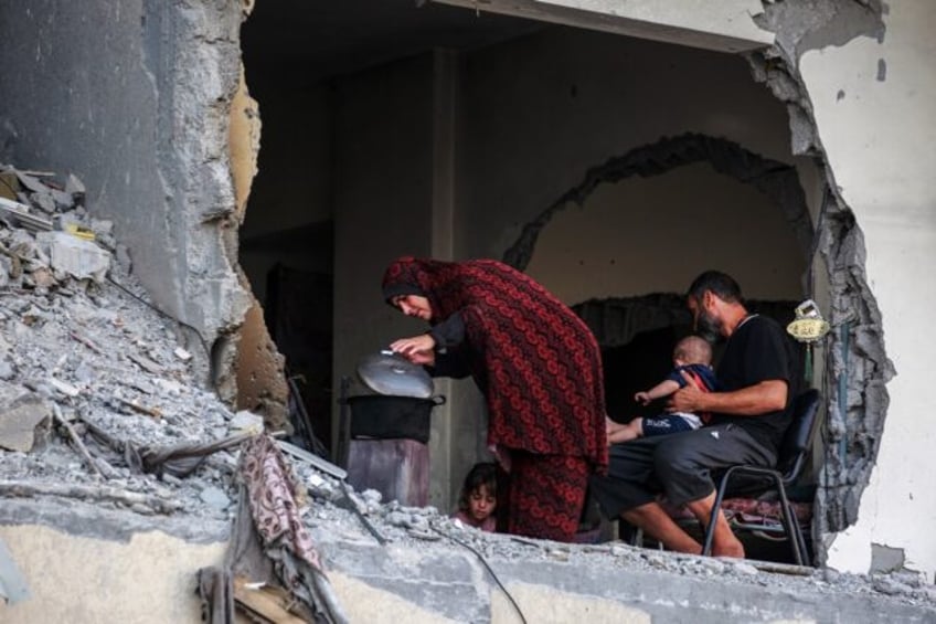 A Palestinian family gathers around a makeshift wood stove in a damaged building in Khan Y