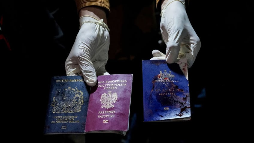 A man displays blood-stained British, Polish, and Australian passports after an Israeli airstrike