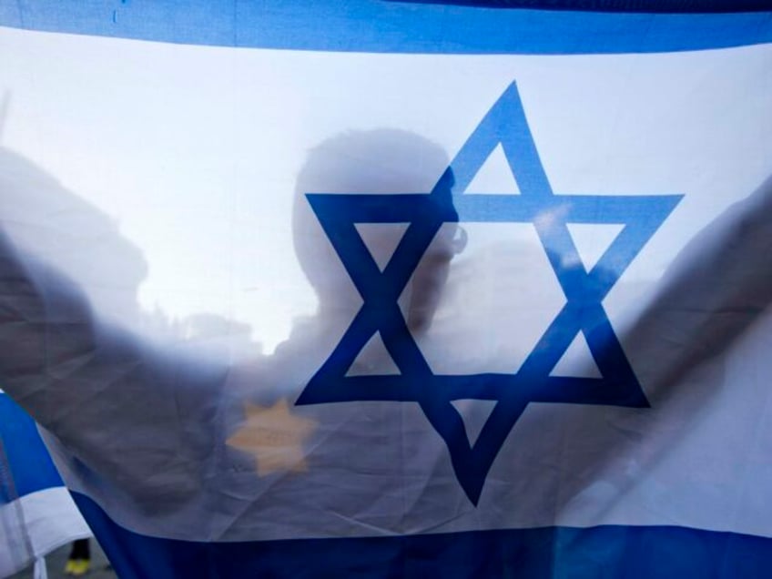 FILE - In this July 14, 2014 photo, a right-wing Israeli holds a flag and wears a Star of