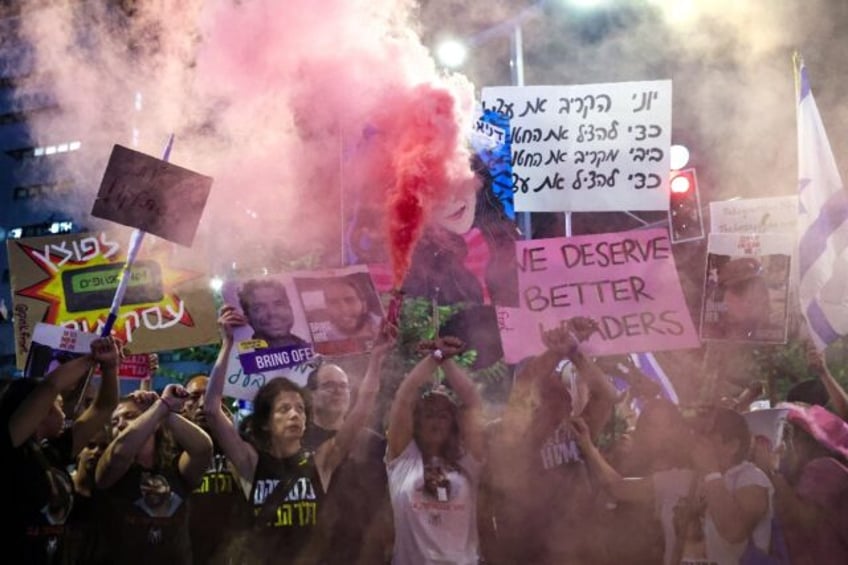 Demonstrators hold placards and set off smoke bombs during an anti-government rally in Isr