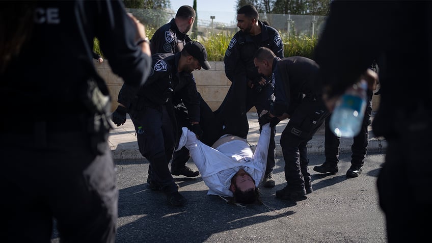 Israeli police officers remove an ultra-Orthodox Jewish man from the street during a protest